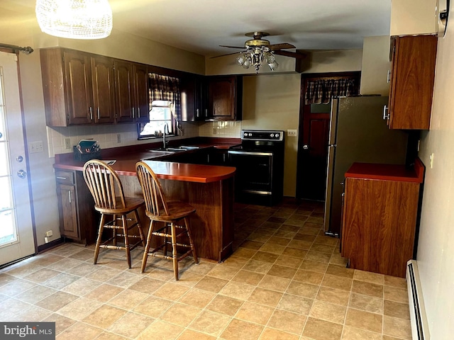 kitchen featuring a breakfast bar, sink, tasteful backsplash, electric range, and a baseboard radiator