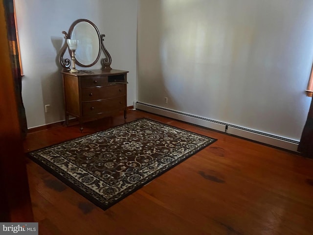 bedroom featuring a baseboard heating unit and hardwood / wood-style flooring