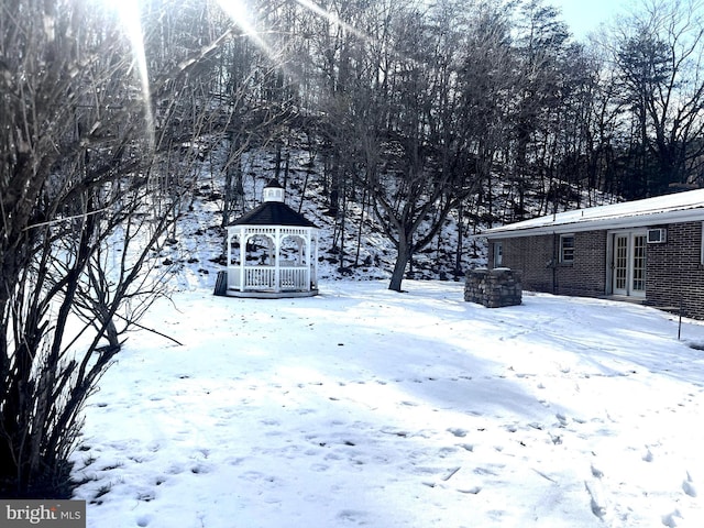 yard layered in snow with a gazebo and french doors