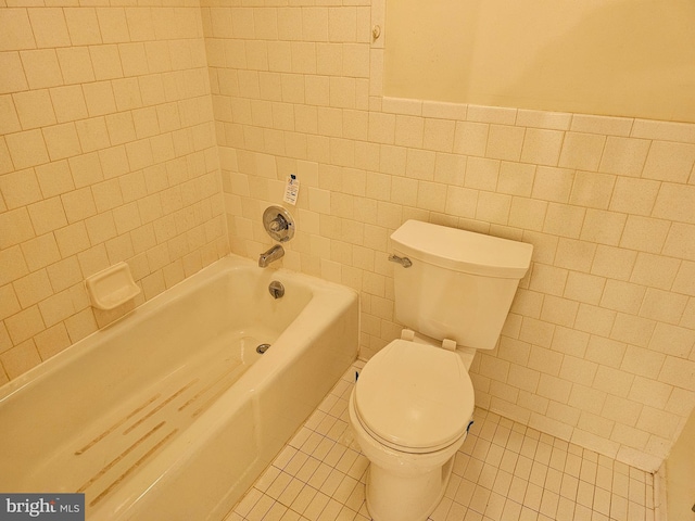 bathroom with tile patterned floors, toilet, tiled shower / bath combo, and tile walls