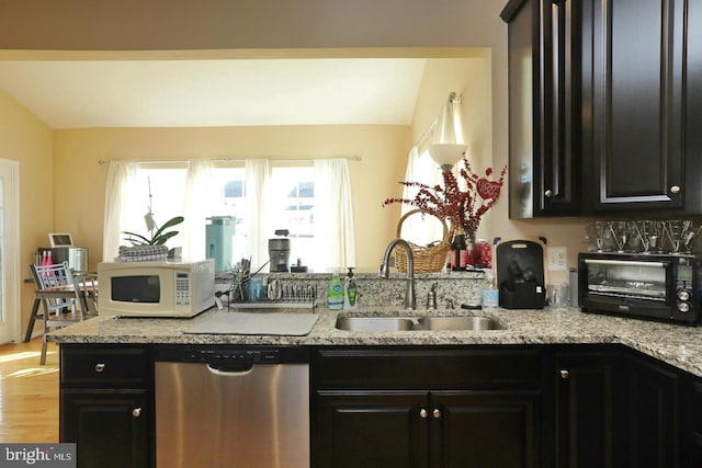 kitchen featuring lofted ceiling, sink, light wood-type flooring, dishwasher, and light stone countertops