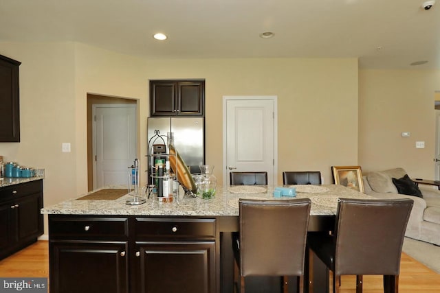 kitchen featuring dark brown cabinets, a center island, a breakfast bar area, and stainless steel fridge with ice dispenser