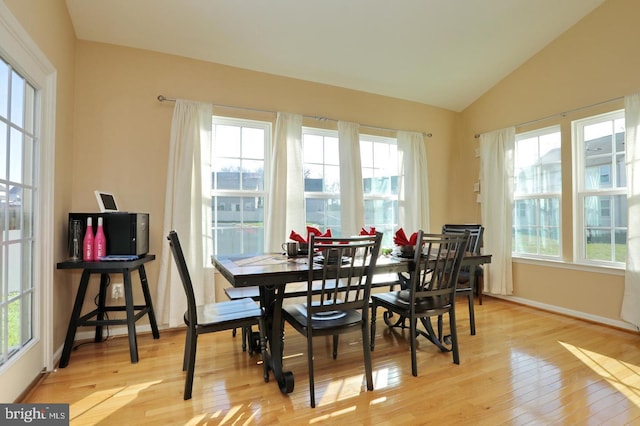 dining space featuring vaulted ceiling and light hardwood / wood-style floors