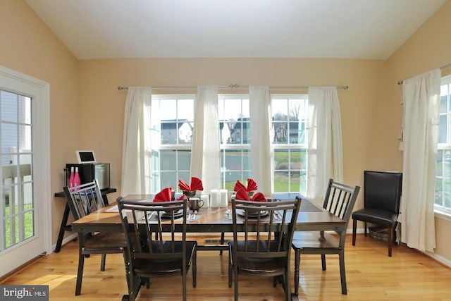 dining space featuring plenty of natural light, lofted ceiling, and light hardwood / wood-style floors