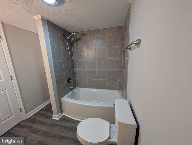 bathroom with tiled shower / bath combo, wood-type flooring, toilet, and a textured ceiling