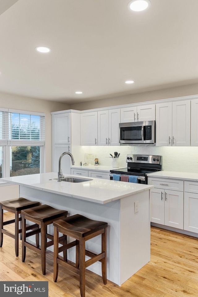 kitchen featuring stainless steel appliances, a kitchen breakfast bar, and a kitchen island with sink