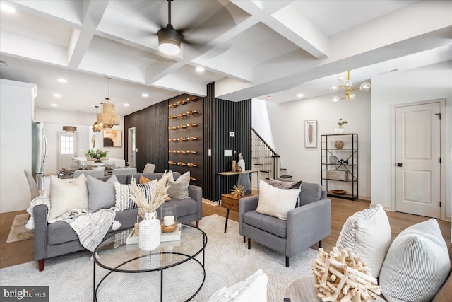 living room with coffered ceiling, beam ceiling, a chandelier, and light wood-type flooring