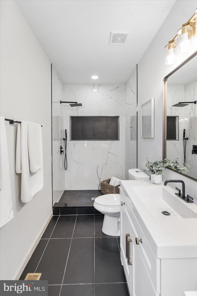 bathroom with vanity, tile patterned flooring, toilet, and tiled shower