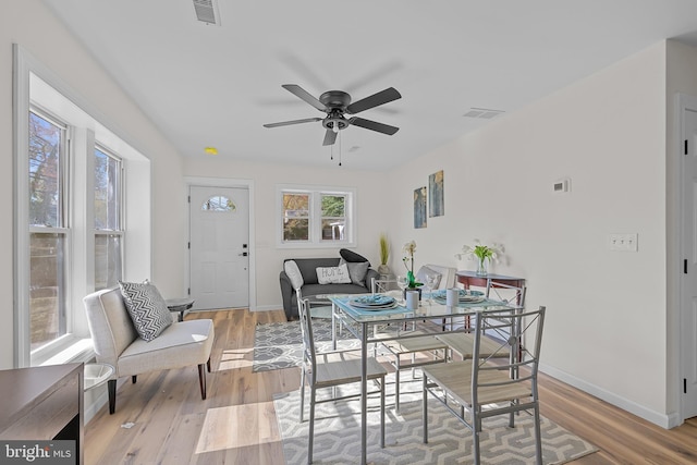 dining space with ceiling fan and light hardwood / wood-style flooring