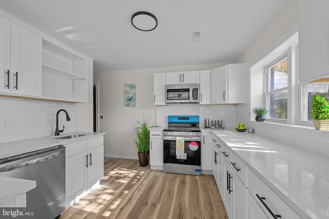 kitchen featuring sink, stainless steel appliances, white cabinets, and light stone countertops