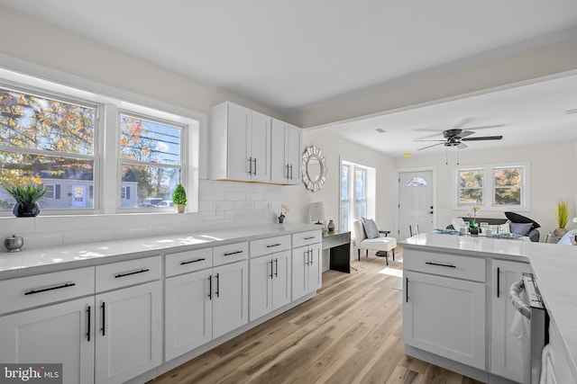 kitchen with white cabinetry, decorative backsplash, light hardwood / wood-style flooring, and light stone countertops