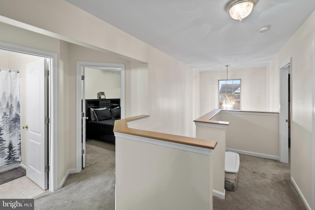 hall featuring an inviting chandelier and light carpet