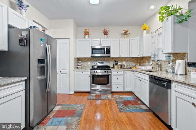 kitchen with white cabinetry, stainless steel appliances, sink, and backsplash