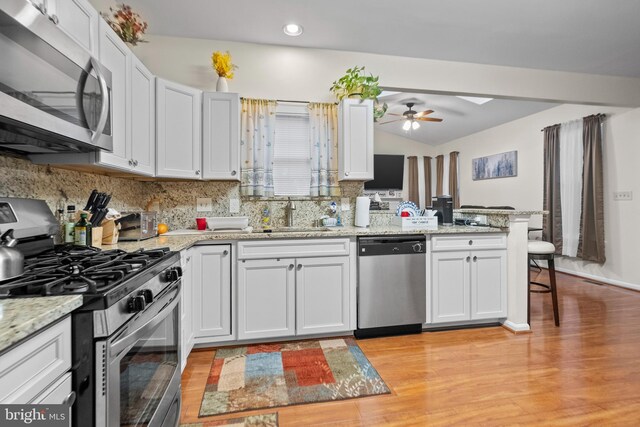 kitchen featuring appliances with stainless steel finishes, kitchen peninsula, sink, and white cabinets