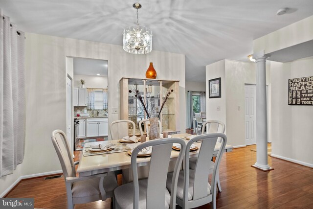 dining space with ornate columns, a chandelier, and light hardwood / wood-style flooring