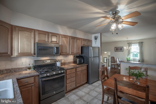 kitchen with stainless steel appliances, decorative light fixtures, decorative backsplash, and dark stone counters