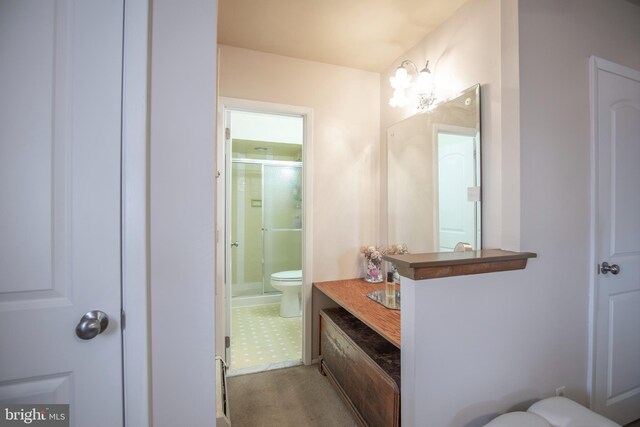 bathroom featuring an inviting chandelier, vanity, toilet, and a shower with door