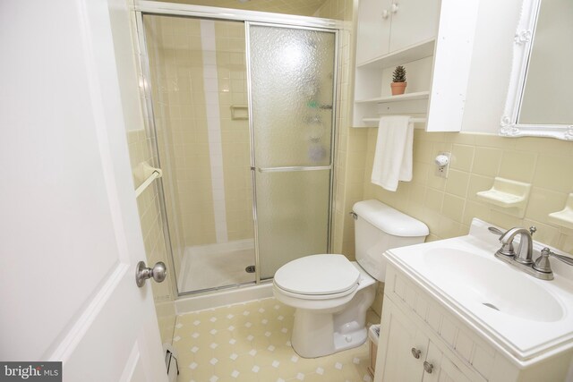 bathroom with walk in shower, vanity, toilet, and tile walls