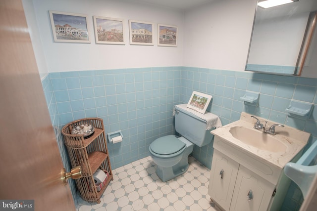 bathroom featuring vanity, toilet, and tile walls