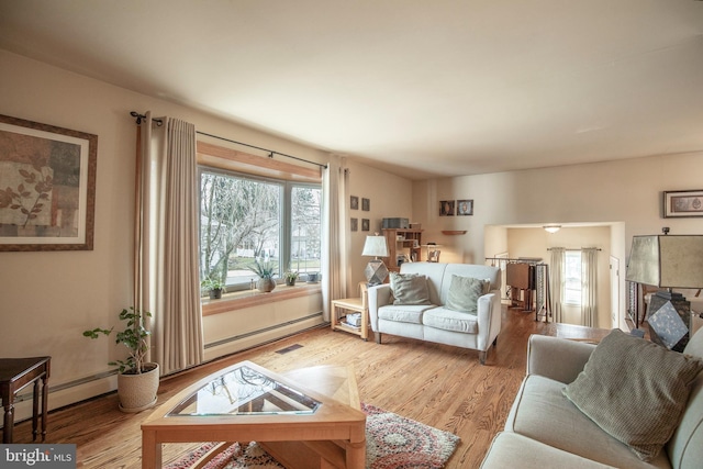 living room featuring a baseboard heating unit, light hardwood / wood-style flooring, and plenty of natural light