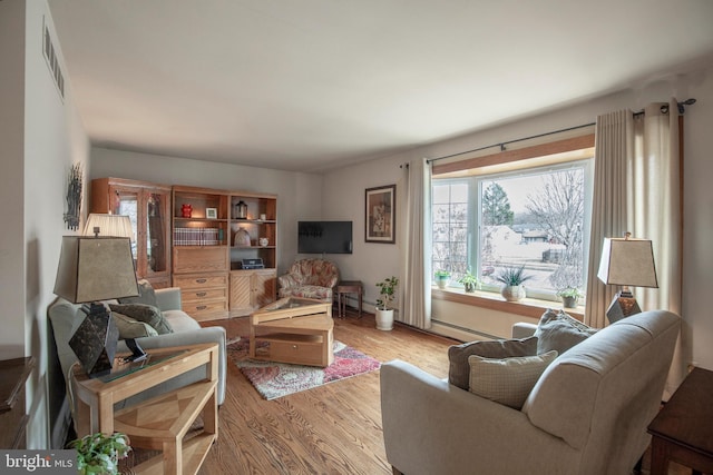 living room featuring a baseboard heating unit and light wood-type flooring