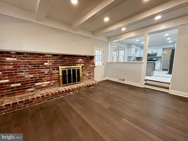 unfurnished living room featuring beamed ceiling, dark wood-type flooring, sink, and a fireplace