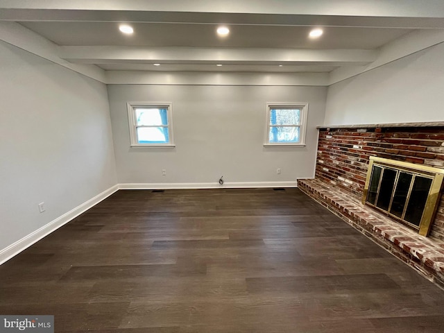 unfurnished living room with beam ceiling, dark wood-type flooring, a wealth of natural light, and a fireplace