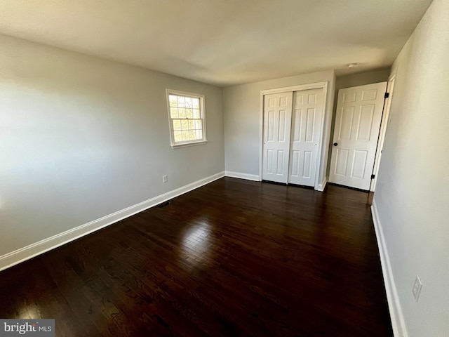 unfurnished bedroom with dark wood-type flooring and a closet