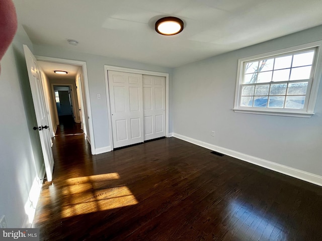 unfurnished bedroom featuring dark hardwood / wood-style floors and a closet