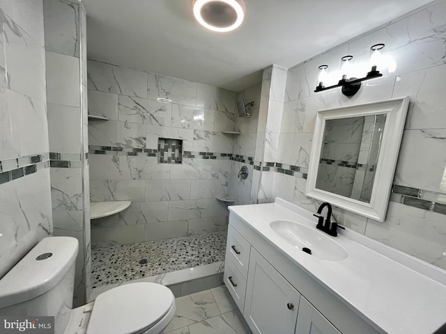 bathroom featuring tiled shower, vanity, toilet, and tile walls