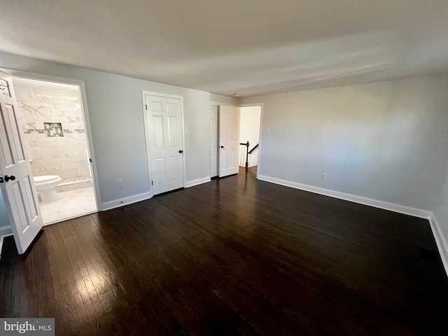 unfurnished bedroom with ensuite bathroom and dark hardwood / wood-style floors