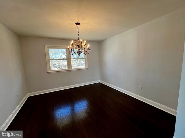 spare room featuring a chandelier and dark hardwood / wood-style flooring