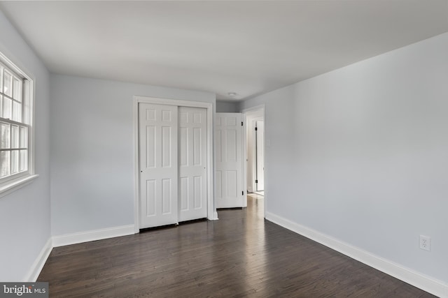 unfurnished bedroom featuring dark hardwood / wood-style flooring and a closet