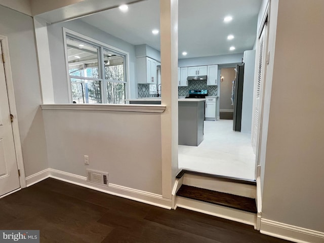 interior space featuring white cabinetry, dark wood-type flooring, backsplash, and stainless steel refrigerator