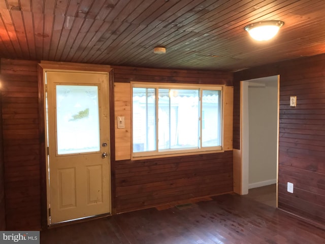 foyer entrance featuring dark hardwood / wood-style flooring, wood ceiling, and wooden walls