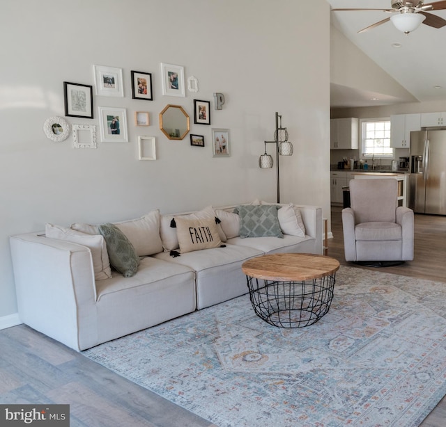 living room with lofted ceiling, sink, light hardwood / wood-style flooring, and ceiling fan