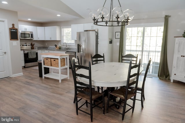 dining area with an inviting chandelier, sink, and light hardwood / wood-style floors