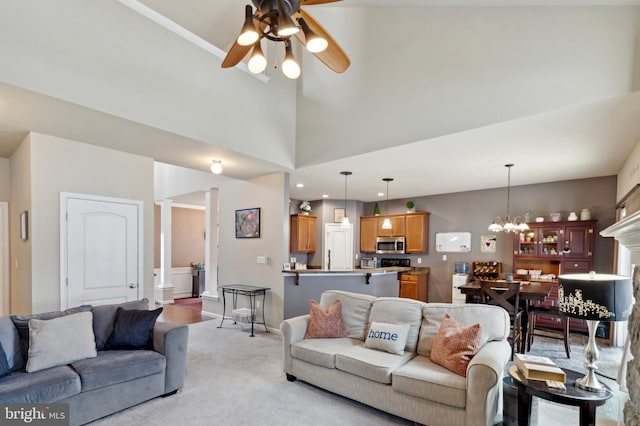 carpeted living room featuring a towering ceiling and ceiling fan with notable chandelier