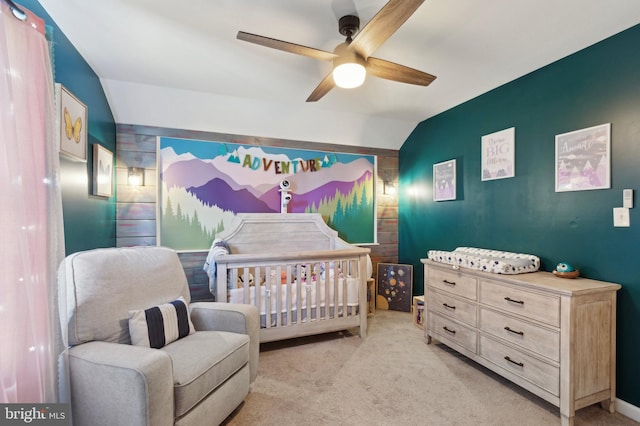 carpeted bedroom with a nursery area, ceiling fan, and vaulted ceiling