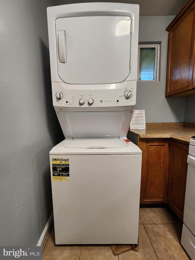 clothes washing area featuring cabinets, stacked washer / drying machine, and light tile patterned floors