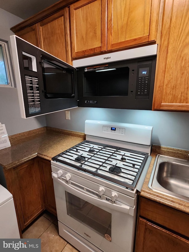 kitchen with sink, white gas stove, and light tile patterned floors