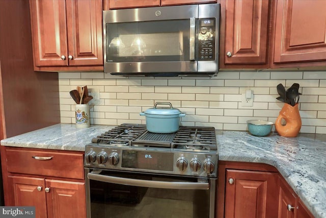 kitchen with light stone counters, backsplash, and stainless steel appliances