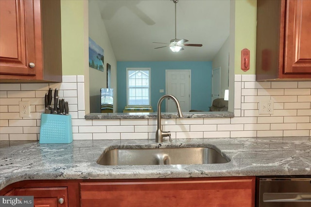 kitchen featuring stone countertops, lofted ceiling, sink, decorative backsplash, and ceiling fan