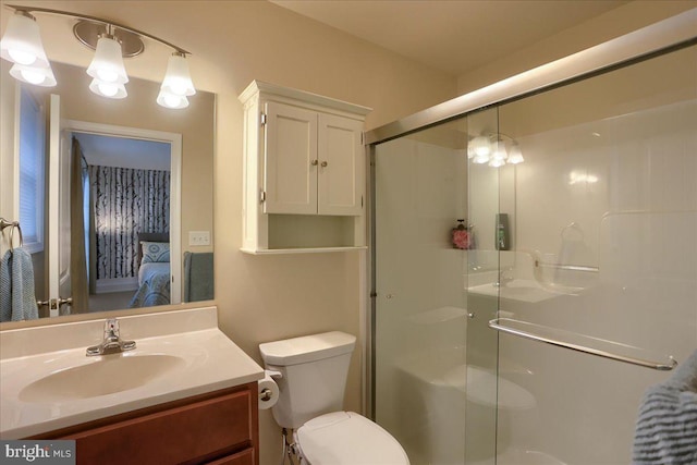 bathroom with vanity, a shower with door, and toilet