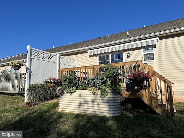 rear view of property featuring a deck and a lawn