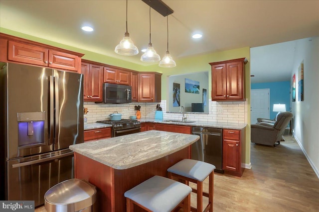 kitchen featuring a kitchen island, sink, a kitchen bar, black appliances, and light stone countertops