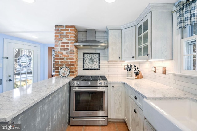 kitchen with white cabinetry, stainless steel gas range, backsplash, and wall chimney exhaust hood