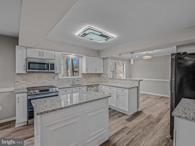 kitchen with stainless steel appliances, a center island, sink, and white cabinets