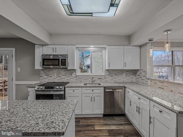 kitchen with white cabinetry, appliances with stainless steel finishes, decorative light fixtures, and sink