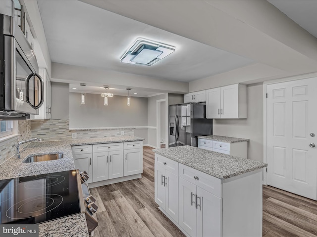 kitchen with pendant lighting, sink, white cabinets, and appliances with stainless steel finishes